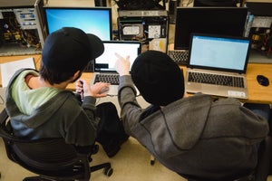 two programming students looking at a laptop